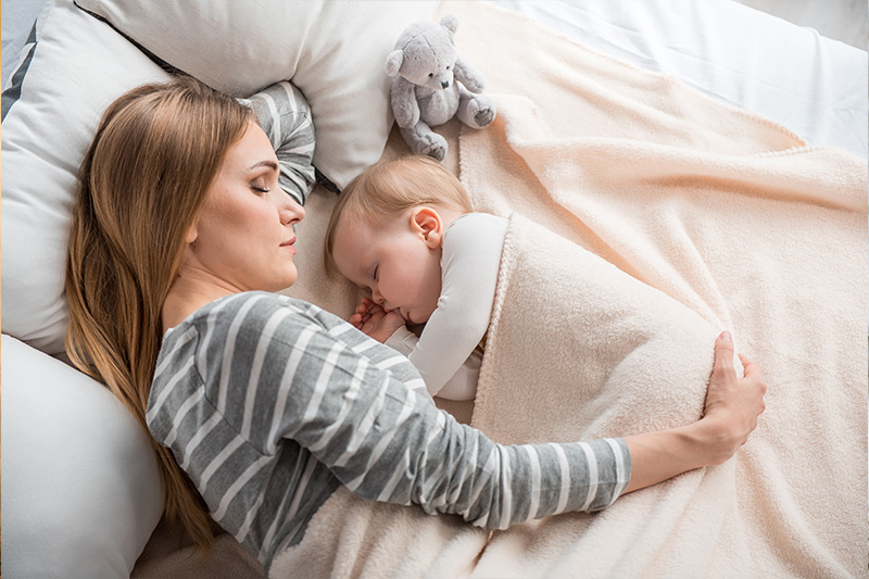 Parent comforting baby in bed